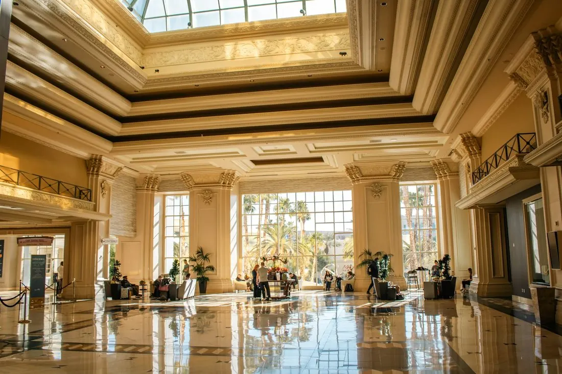Vestíbulo de hotel con piso pulido, columnas altas y tragaluz