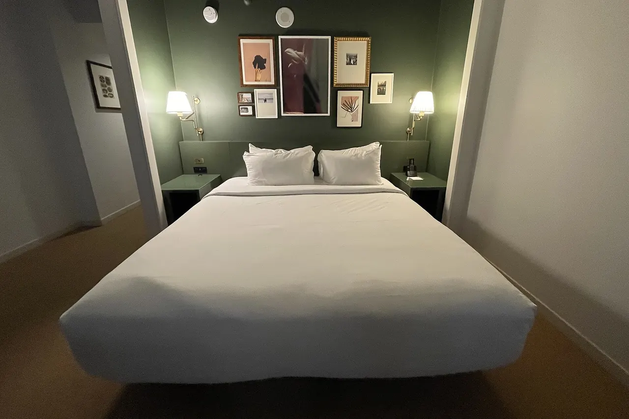 Cama recién tendida con ropa de cama blanca en una habitación de hotel